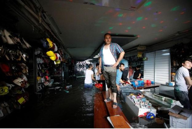 أصحاب متاجر يحاولون إنقاذ بضائعهم من مياه أمطار اجتاحت البازار الكبير التاريخي باسطنبول يوم السبت. تصوير: كمال أصلان - رويترز